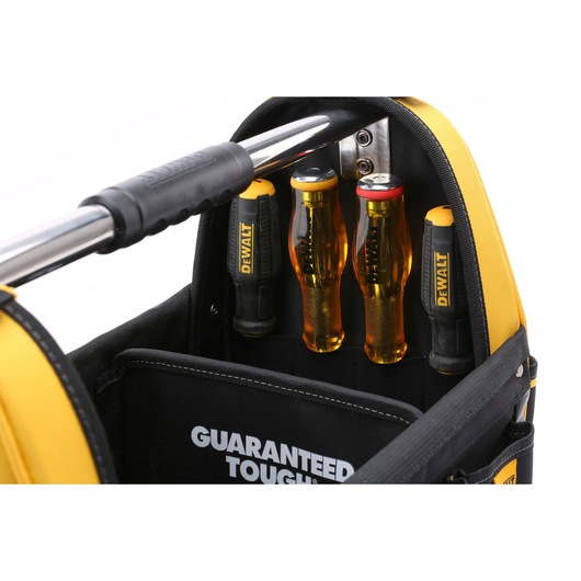 Close-up of a DEWALT tool bag with a metal handle and several DEWALT branded screwdrivers stored upright in inside pockets. The words 'GUARANTEED TOUGH' are visible on a black inner panel.