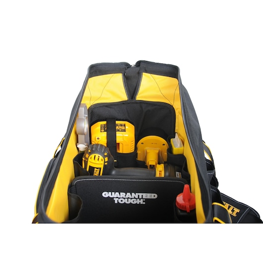 Top view of an open DEWALT tool bag filled with various tools including a yellow and black drill, a tape measure, and other hand tools. The inside of the bag displays the words 'GUARANTEED TOUGH.'