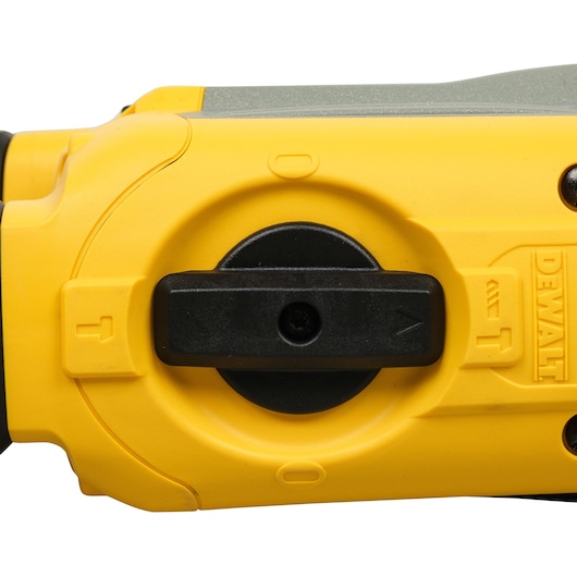 Close-up image of a yellow DEWALT power tool, showing a selector switch with directional arrows and DEWALT branding embossed on the housing.