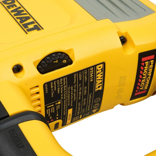 Close-up image of a yellow DEWALT power tool showing the model number D25614K and product label, with a performance protection sticker and adjustment dial.
