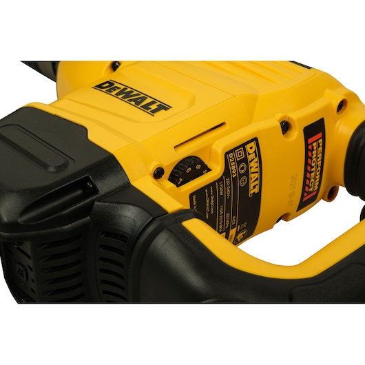 Close-up of a DEWALT electric power tool, showing part of the yellow and black body, a control dial, and product labels. The labels include the DEWALT brand name and technical specifications.