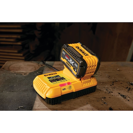 A DEWALT battery charger with a battery pack attached, placed on a workbench in a workshop setting.