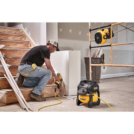 FLEXVOLT® 2.5 GALLON CORDLESS AIR COMPRESSOR being used by a person to power a pneumatic nailer for countersinking holes in a wood scotting