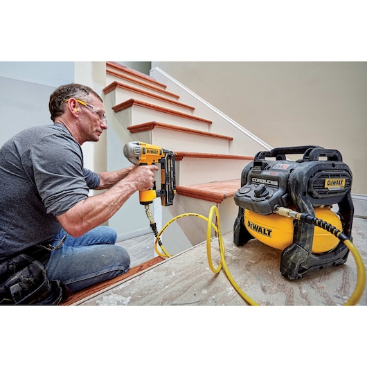 FLEXVOLT® 2.5 GALLON CORDLESS AIR COMPRESSOR being used by a person to power a pneumatic nailer