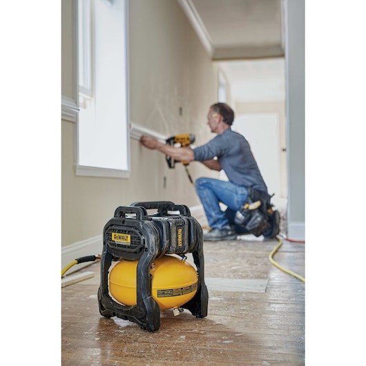 FLEXVOLT® 2.5 GALLON CORDLESS AIR COMPRESSOR being used by a worker to power a pneumatic nailer for fastening