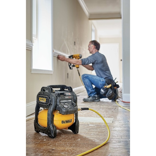 FLEXVOLT® 2.5 GALLON CORDLESS AIR COMPRESSOR being used by a person to power a pneumatic nailer