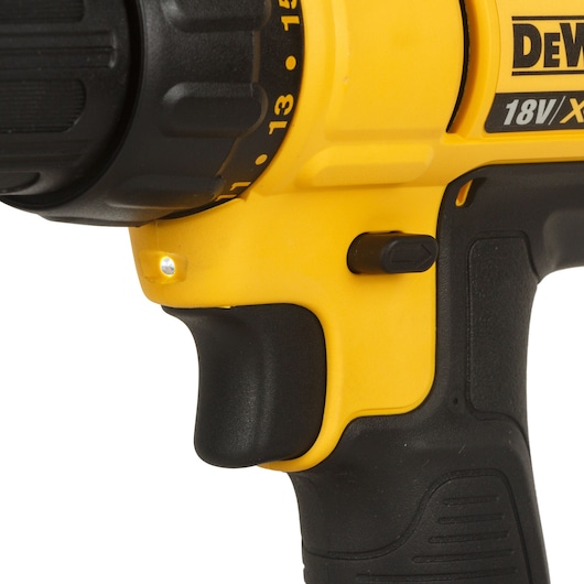 Close-up view of a yellow and black Dewalt cordless drill with visible trigger, LED light, and grip.