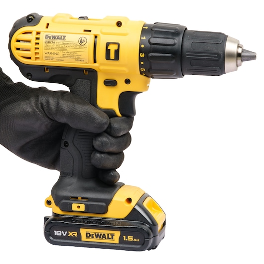 A close-up image of a yellow and black DEWALT cordless drill (model DCD776S2A, 18V XR, 1.5Ah) being held in a gloved hand.
