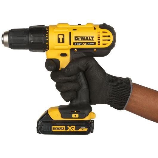 A DEWALT 18V XR Li-Ion cordless drill held by a person wearing a black work glove, showing the drill's yellow and black design with visible branding and battery.