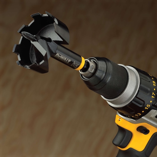 Close-up of a DEWALT cordless drill with a wood hole saw attachment, showing the front part of the drill and the sharp hole saw bit designed for cutting large holes in wood.