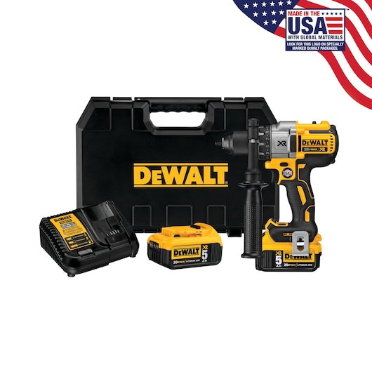 A DEWALT DCD991P2 cordless drill kit is shown, including a black and yellow drill, two rechargeable batteries, a charger, a side handle, and a hard carrying case. The DEWALT logo is prominently displayed on the case and the products. A USA flag graphic in the corner says 'Made in the USA with Global Materials.'