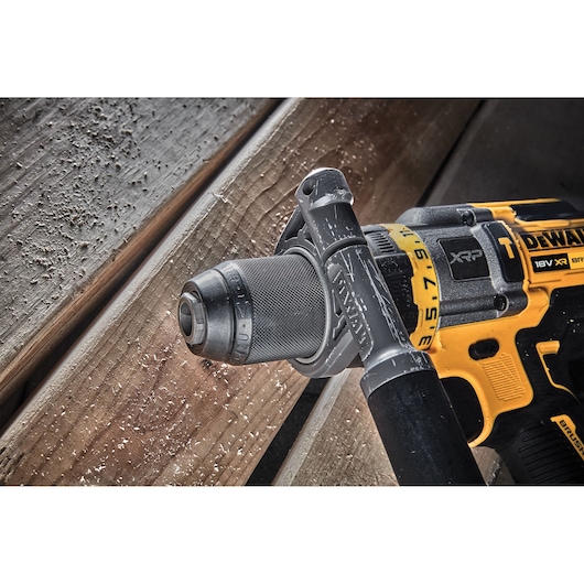 Close-up of a DEWALT DCD999NT 18V XR brushless power drill being used on wooden planks, with wood shavings around the drill.