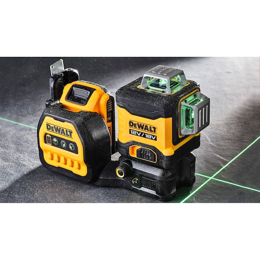 DEWALT laser level tool, model DCE089NG18, shown on a work surface with green laser lines projected, featuring durable yellow and black construction and control buttons.