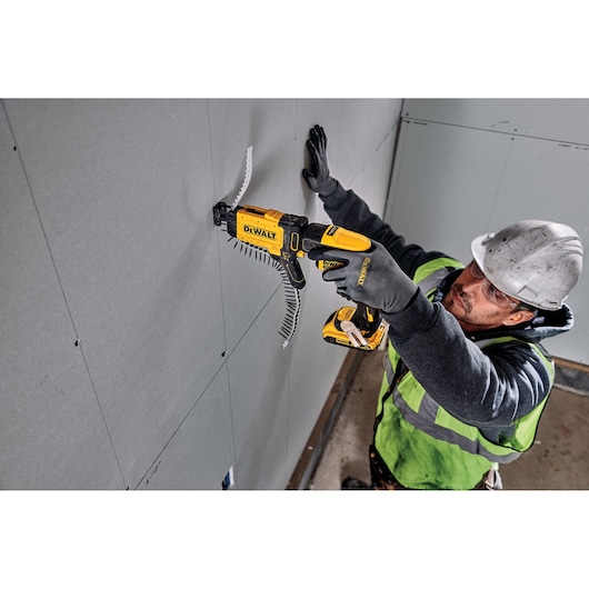 Photo of DEWALT DCF6202 drywall screw gun in use attaching panels, worker in safety gear visible.
