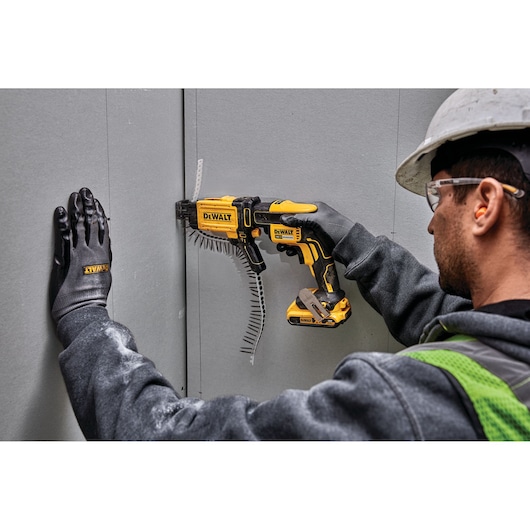 Photo of DEWALT DCF6202 screw gun used on drywall, worker wearing gloves and helmet, close-up action shot.