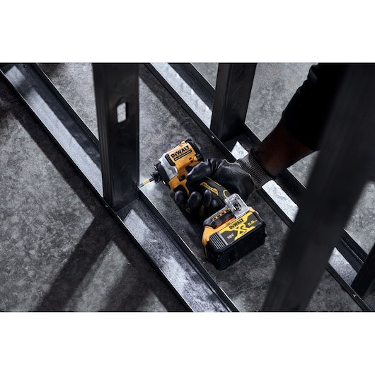 DEWALT DCF850N, DCZ2050P2T-XE, DCZ401P3-XE impact driver held by gloved hand working on metal structure.