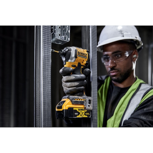 DEWALT tool in use. Visible DCF850N, DCZ2050P2T-XE, DCZ401P3-XE. Worker with glove, hard hat, safety vest.