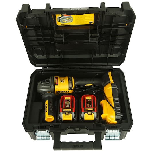 A DEWALT power tool kit containing a cordless angle grinder, two batteries, a charger, and an auxiliary handle, all neatly placed in a hard black carrying case with the lid open.