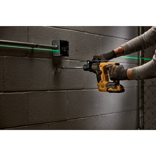 Brushless 9 sixteenth inch S D S PLUS Rotary Hammer Bare Tool being used for pipe clamp anchoring in concrete wall.