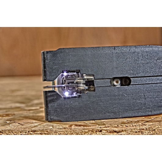 Close-up view of a DEWALT jigsaw blade and cutting mechanism in action on a wooden surface, with built-in LED lights illuminating the work area.
