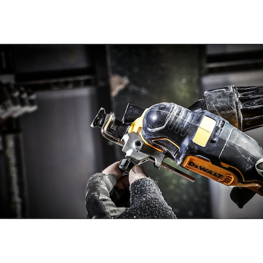 Close-up of a person using a DEWALT DCS356N cordless oscillating multi-tool for cutting metal, wearing work gloves.