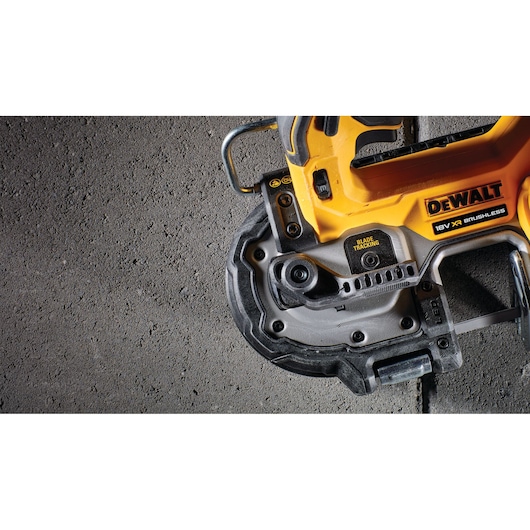 Close-up of a DEWALT 18V XR Brushless power tool, specifically showing the blade tracking feature and part of the handle against a textured concrete surface.