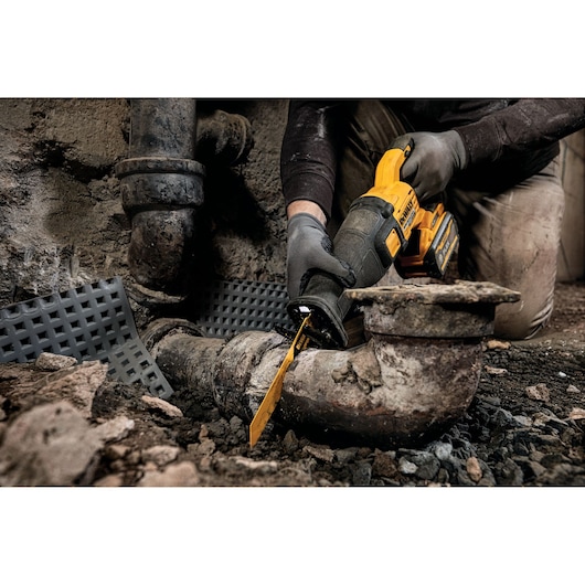 FLEXVOLT brushless cordless reciprocating saw being used to cut drainage pipe.