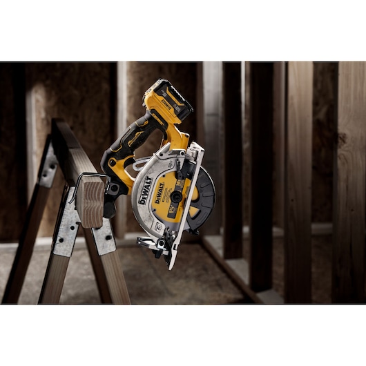 Xtreme 12 volt 5 and three eighths inch brushless cordless circular saw tool being hanged to a plank at a construction site.