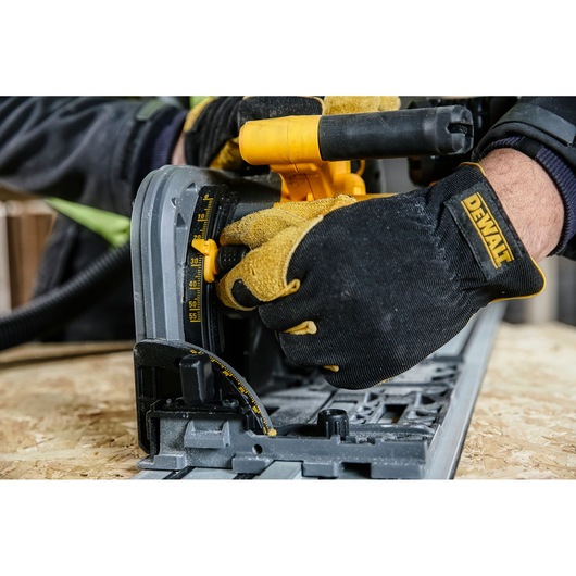 Close-up of gloved hands adjusting a DEWALT circular saw on a wooden surface.