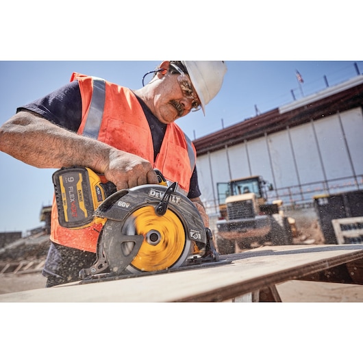 FLEXVOLT brushless cordless circular saw with brake kit being used by person to cut wood.