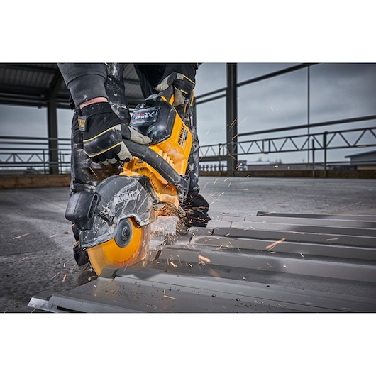 DEWALT saw cutting metal with sparks flying, operated by a person wearing gloves on an industrial site.
