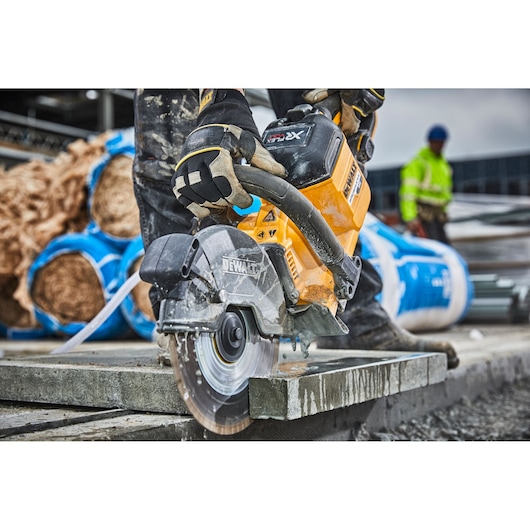 Worker uses a DEWALT DCS690N circular saw to cut concrete at a construction site.