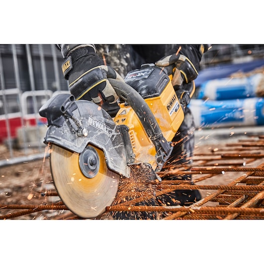 DEWALT cutter slicing metal rebar at a construction site, sparks flying from the circular blade.