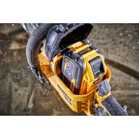 Close-up of a DEWALT cordless power tool with an 18V battery installed, placed on a dusty surface.