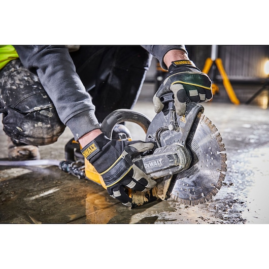 DEWALT worker uses power cut-off saw on wet concrete floor, wearing gloves and work clothes.