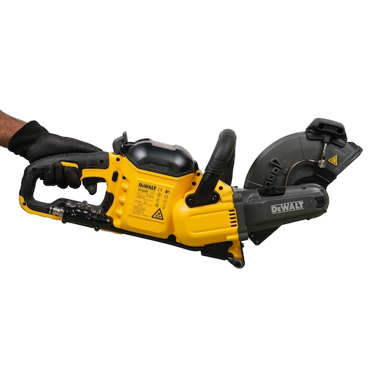 A person wearing a black glove holds a DEWALT DCS690N yellow and black cordless cut-off saw against a white background. The tool is designed for cutting various materials and features visible safety and manufacturer labeling.