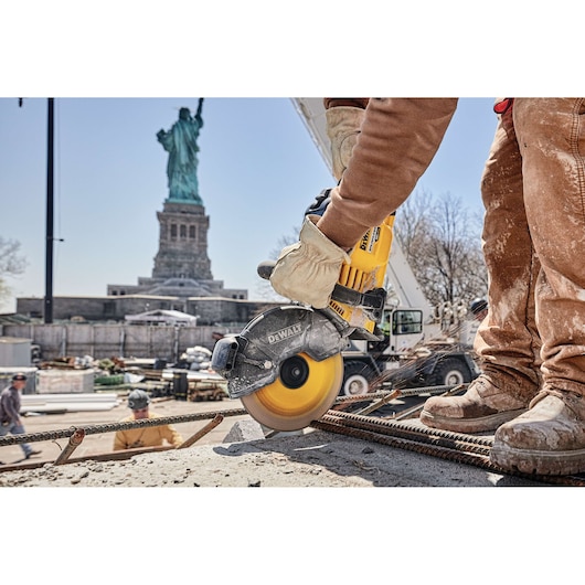 Photo of DEWALT DCS690X2 cut-off saw cutting rebar at a construction site, Statue of Liberty in background.