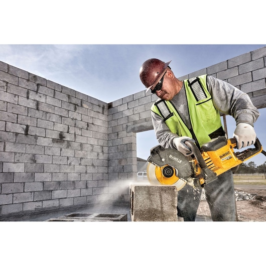 Worker uses a DEWALT cordless cut-off saw to cut concrete blocks at a construction site.