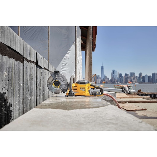 DEWALT DCS690X2 power tool placed on a construction site, with a city skyline visible in the background.