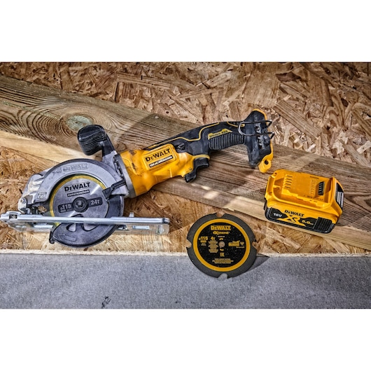 DEWALT cordless circular saw with blade, spare disc, and battery placed on a wooden board.