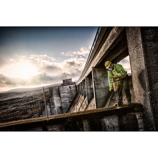 Worker uses DEWALT tool, DT60814, DT60814-QZ, on concrete at construction site. Photography category.