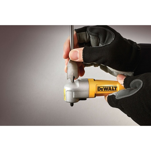 Two gloved hands hold a DEWALT branded right-angle drill attachment while inserting a drill bit, against a neutral background.