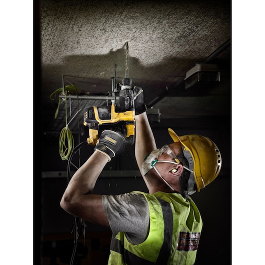 Worker uses DEWALT drill bits DT9580, DT9580-QZ for ceiling work; safety gear worn. Photography product.
