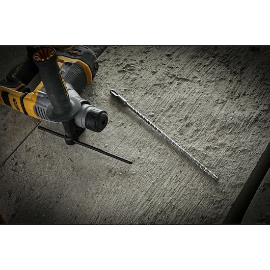 SDS Plus 6mm drill bit sitting on concrete alongside SDS Plus hammer drill