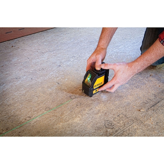 Green cross line laser being used by a person.