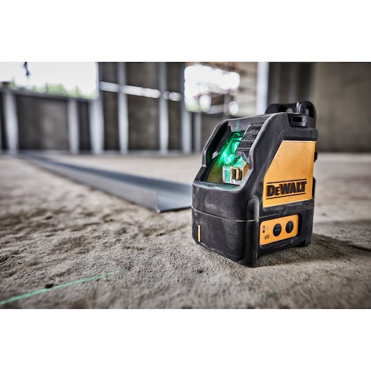 DEWALT green beam laser level DW088CG placed on a concrete floor inside a construction site.