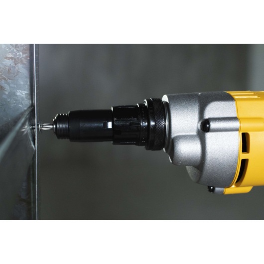 Close-up view of a yellow and silver DEWALT power screwdriver (model DW268) driving a screw into a metal surface.