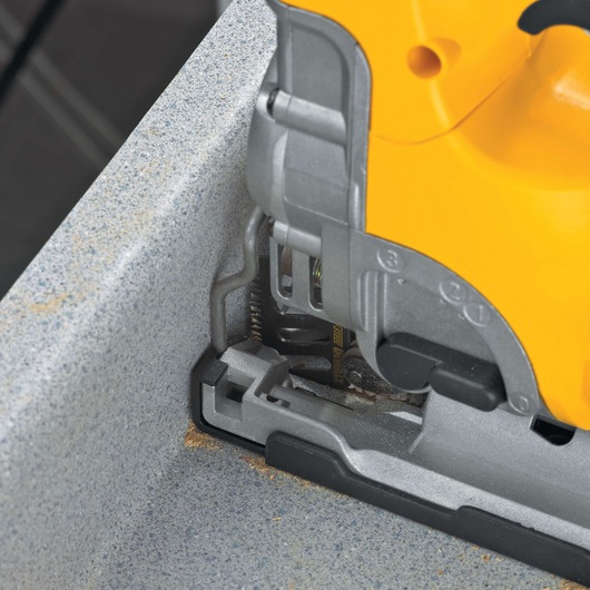 Close-up of a DEWALT jigsaw cutting through a gray stone or composite countertop.