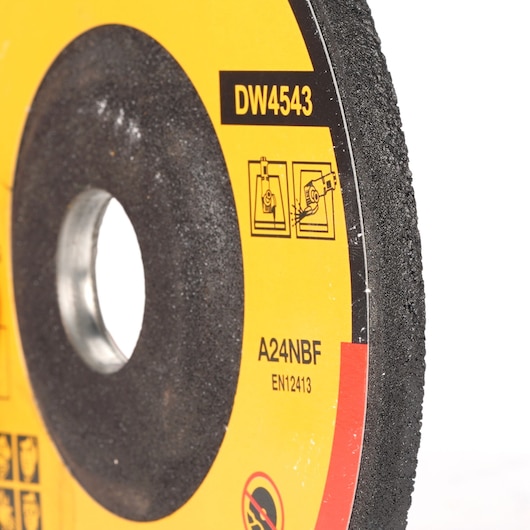 Close-up of a DEWALT DW4543 abrasive cutting disc, mainly black with a yellow label showing usage and safety icons, as well as the model number and technical specifications.