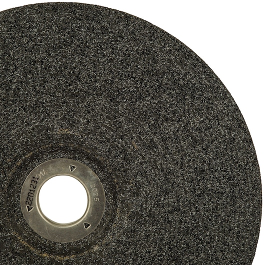 Close-up view of a DEWALT abrasive cutting disc with a rough textured surface and a metal center hole, partially shown against a white background.